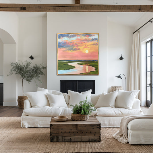 Charleston marsh sunset oil painting with melon and periwinkle sky in a gold floater frame, styled above a neutral sofa in a luxury coastal living room.