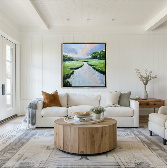 Large square Lowcountry evening art 'Periwinkle Reflection' styled in a gold frame within a coastal modern Savannah living room, showcasing deep navy and pink twilight tones.