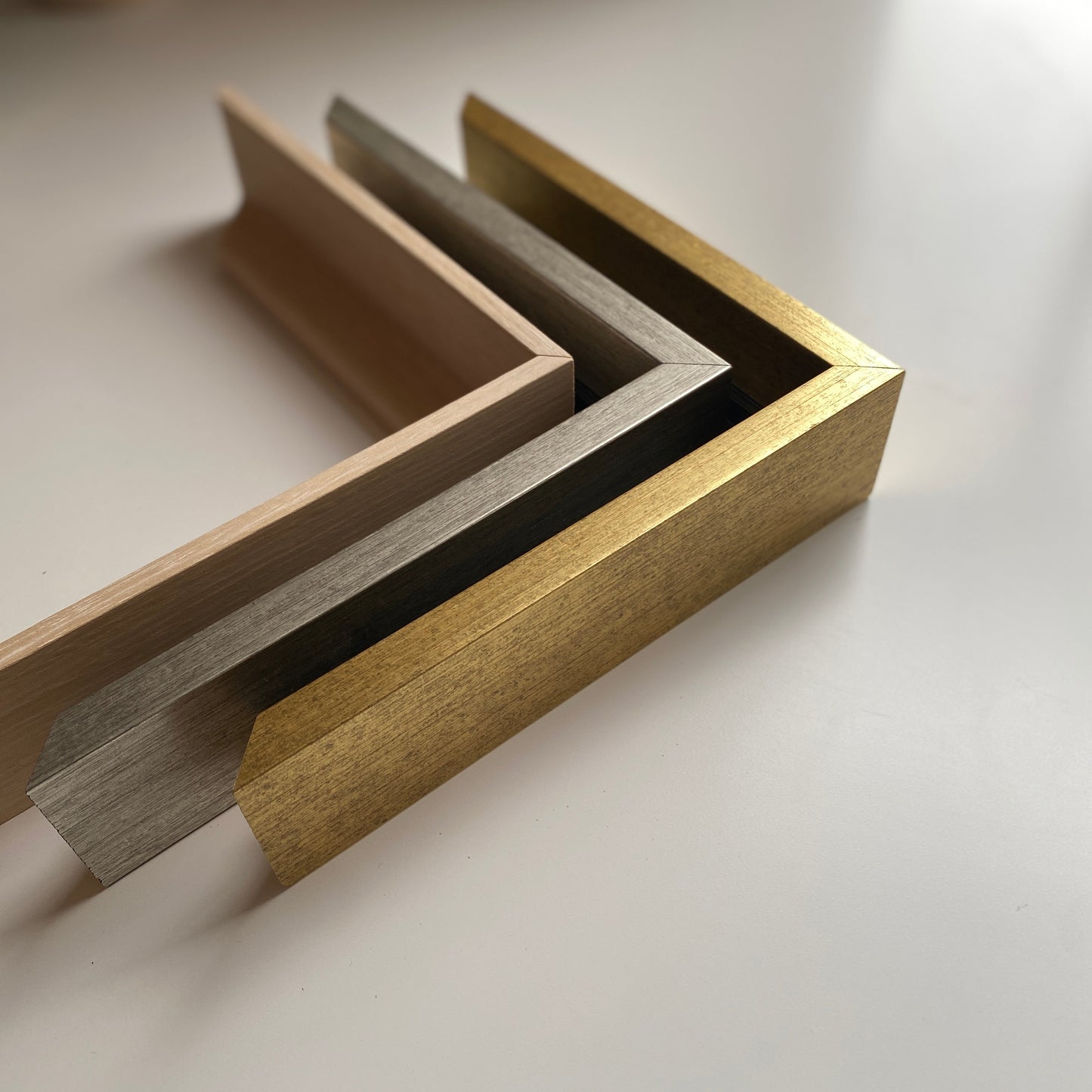 Close-up of a gold, silver, and wood 1.5" floater frames that customers may choose
