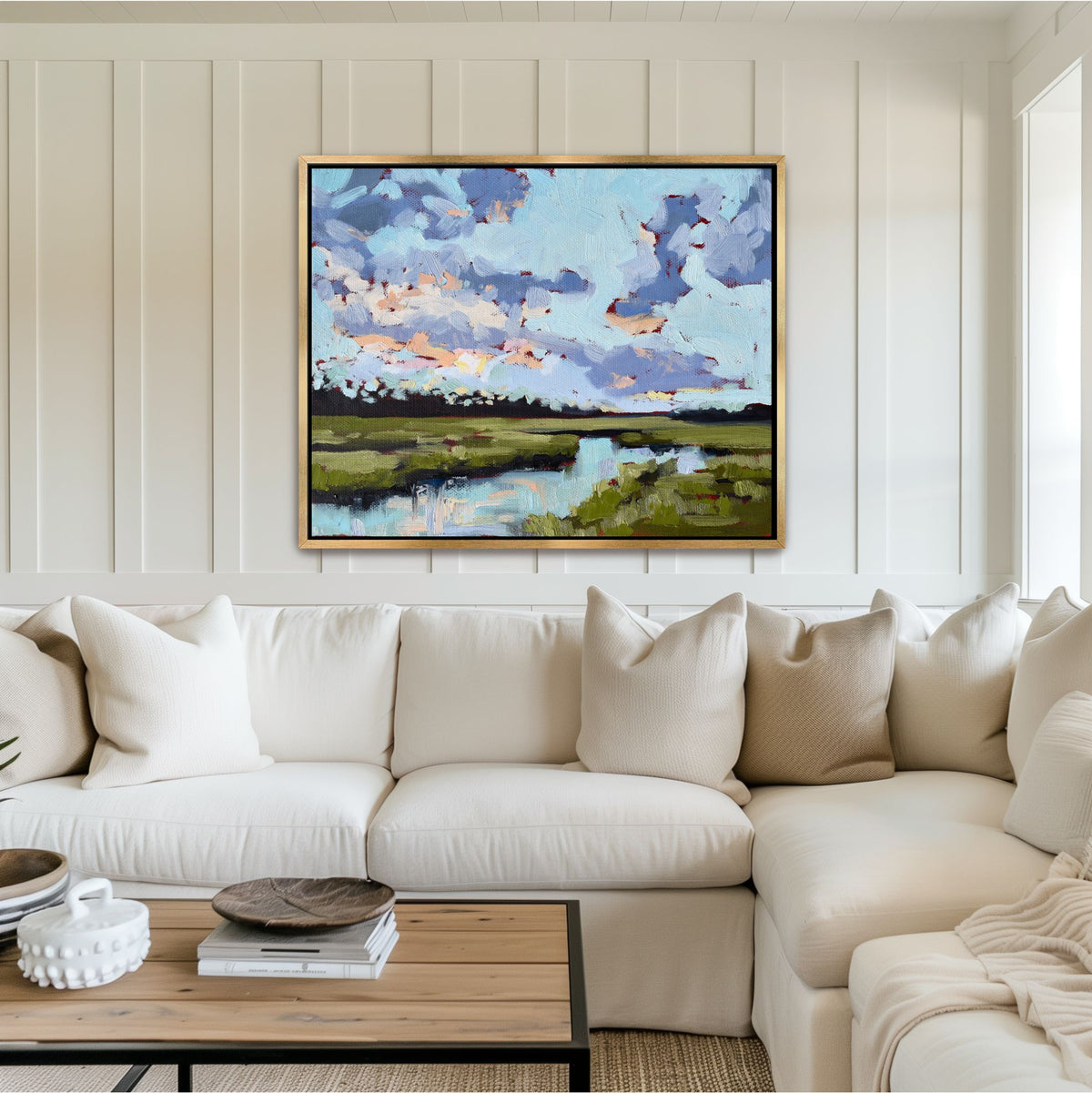 Jekyll Island Morning marsh painting in a gold frame, showcasing the luminous glow of pale blue and periwinkle over a red underpainting, styled in a luxury living room.