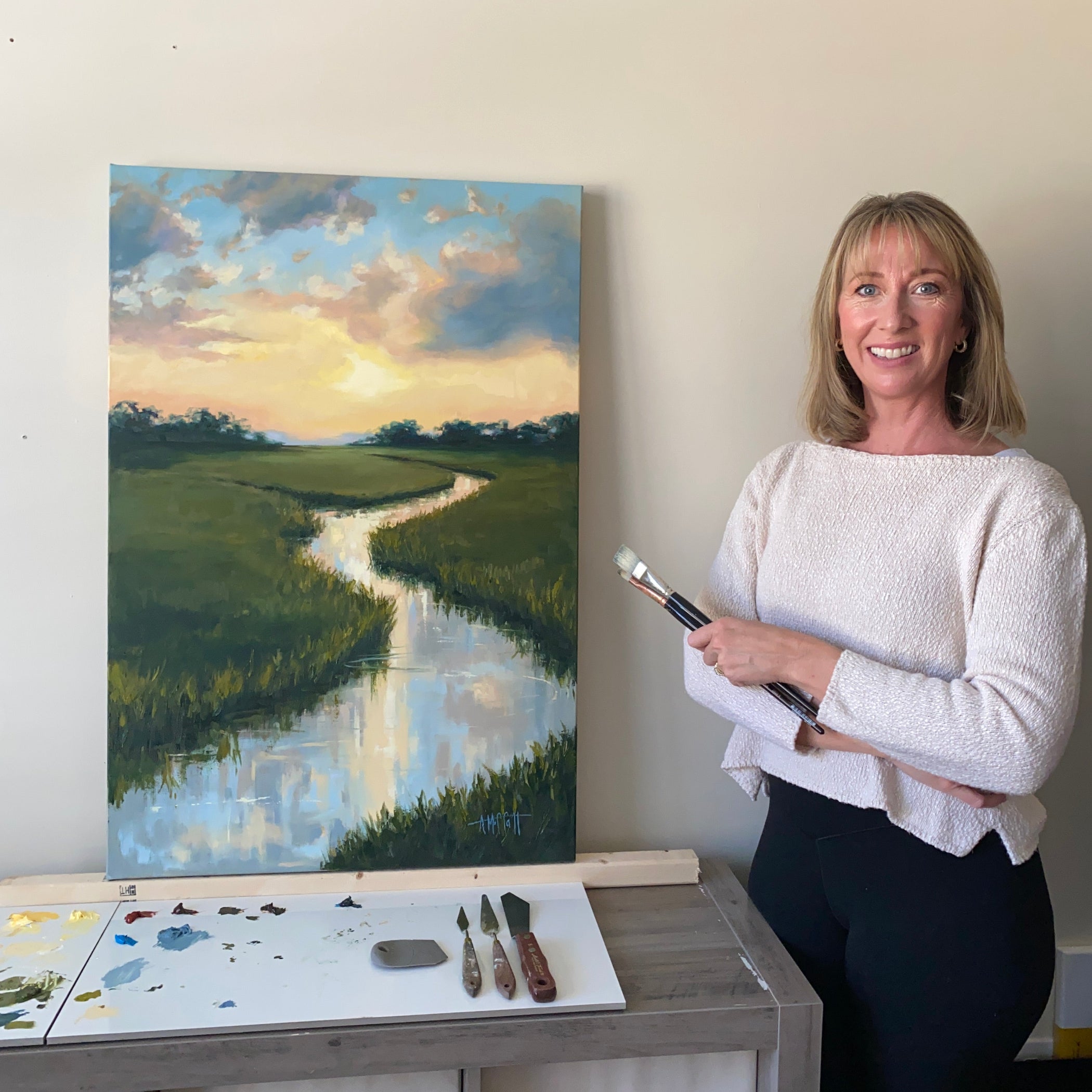 April in her studio with a freshly painting oil painting " Serenity" in the Lowcountry Tidal Creek
